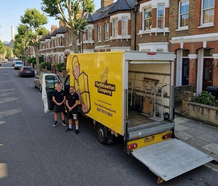 Yellow Van Company on a residential Battersea street with Battersea Power Station in the background &mdash; family-run removals across SW8 and SW11 since 2011