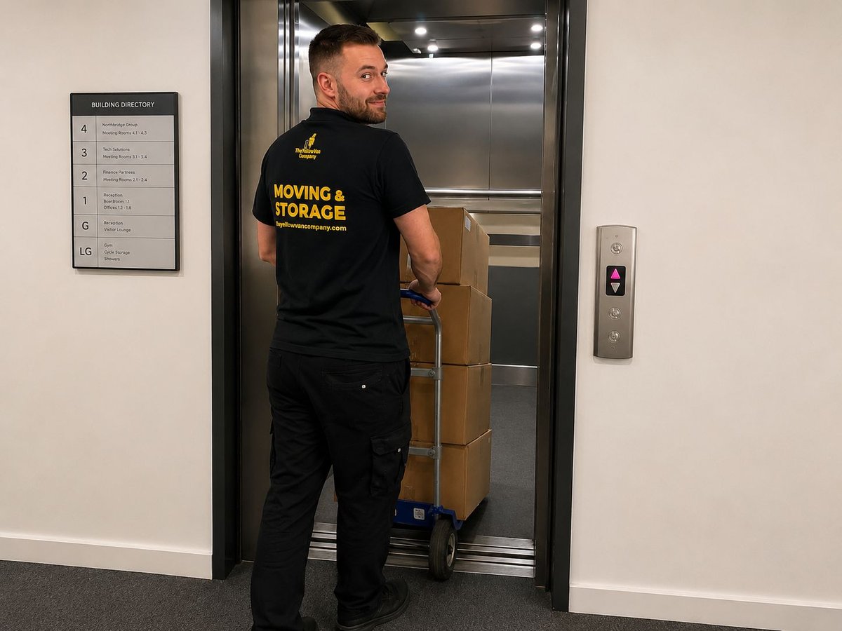 Yellow Van Company mover with a wheeled trolley loaded with office boxes during a London office relocation &mdash; professional, careful commercial removals across the capital